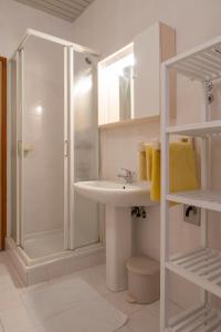a white bathroom with a shower and a sink at Apartmani MIRA in Premantura