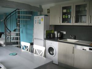 a kitchen with a white refrigerator and a washing machine at La Pomme Verte in Authou