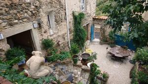un jardín con una estatua, una mesa y plantas en La belle endormie, en Cabrerolles