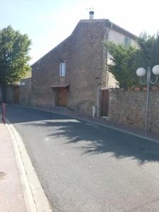 un antiguo edificio de piedra con una carretera delante de él en Chambre d'Hôtes le massanous, en Laure-Minervois