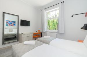 a white bedroom with two beds and a mirror at Zefiro Stajenna in Gdańsk