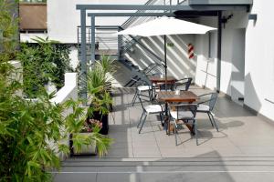 un patio con tavoli, sedie e ombrellone di Abril Hotel Boutique a Mendoza