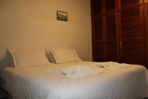 a bed with white sheets and towels on it at Casa de Lazer em Campos do Jordao in Campos do Jordão