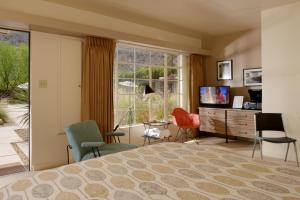 a bedroom with a bed and chairs and a television at The Hideaway in Palm Springs