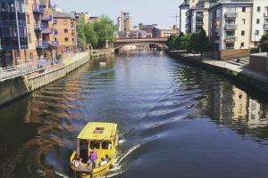 a yellow boat on a river in a city at Leeds City Centre Apartments in Leeds