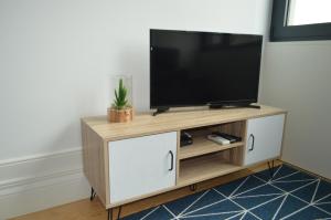 uma televisão num suporte de televisão de madeira numa sala de estar em Camões by Trindade Sweet Home em Porto