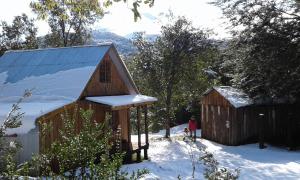 a barn with snow on the roof and a person standing in the snow at Remanso Andino in Palena