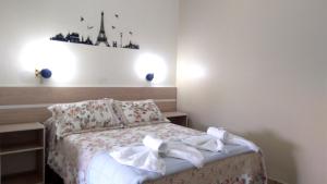 um pequeno quarto com uma cama com toalhas brancas em Hotel Itamiaru em Iguape