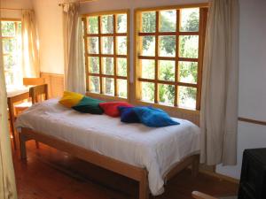 1 cama con almohadas coloridas frente a una ventana en Remanso Andino, en Palena