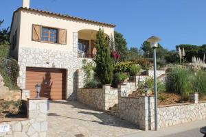 una casa con una pared de piedra y un garaje en Villa Puig Rosell, en Calonge