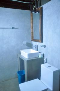 a bathroom with a sink and a toilet and a mirror at Kottawatta Village in Udawalawe