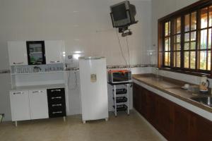 a kitchen with a refrigerator and a tv on the wall at Chácara Martinez in Conservatória
