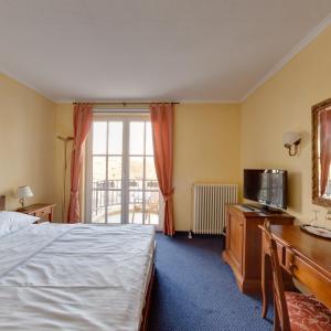 杜伊斯堡的住宿－蘭德斯米爾賽酒店，酒店客房配有一张床、一张书桌和一台电视。