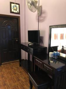 a room with a desk with a television and a mirror at Soutjai Guesthouse & Restaurant in Vang Vieng