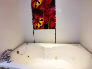 a bathtub in a bathroom with a painting on the wall at Meng Qi Hotel in Taipei