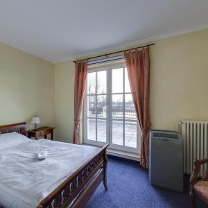 a bedroom with a bed and a large window at Hotel Landhaus Milser in Duisburg