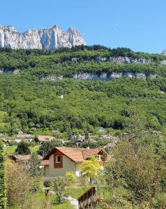 una casa en una colina con montañas en el fondo en Maison Cosy Lac d'Annecy, en Talloires