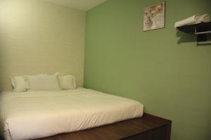 a bedroom with a white bed with a green wall at Hotel Sri Rembia in Melaka