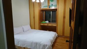 a small bedroom with a white bed and a window at Garden Hostel in Minxiong