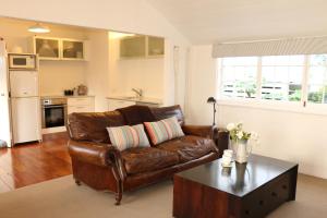 a living room with a brown leather couch and a coffee table at Historic Colenso Cottage in Napier