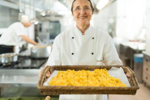 a chef holding a tray of pasta in a kitchen at Hotel Atlantic Riviera Mare in Misano Adriatico