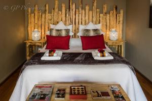 a bedroom with a large bed with red pillows at Laguna Lodge in Graskop
