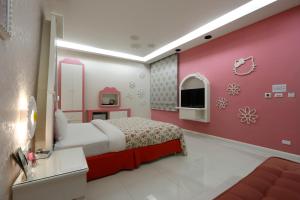 1 dormitorio con cama y pared de color rosa en Hua Xiang Hotel-Qishan, en Qishan