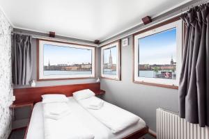 a small room with two beds and two windows at Rygerfjord Hotel & Hostel in Stockholm