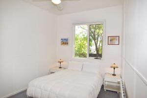 a white bedroom with a bed and a window at 45 HALFORD - PET FRIENDLY in Inverloch