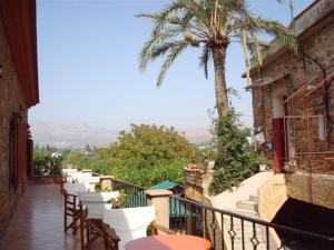 a balcony with tables and chairs and a palm tree at Krini Rooms in Kambos
