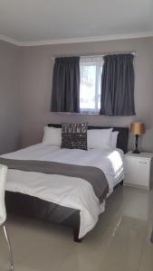 a bedroom with a large white bed with a window at The Brookston Garden Cottage in Cape Town