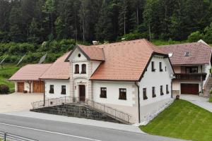 ein weißes Haus mit rotem Dach an der Straßenseite in der Unterkunft Farm stay Bukovje in Ljubno