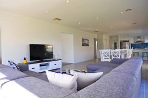 een woonkamer met een bank en een flatscreen-tv bij Plovers Rest in Inverloch