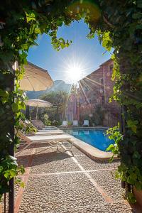 uma vista para uma piscina com uma mesa e um guarda-sol em Hotel y Apartamentos DES PUIG em Deia