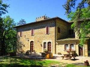 un grand bâtiment en briques avec des tables de pique-nique devant lui dans l'établissement Castello Cortevecchio, à Gubbio
