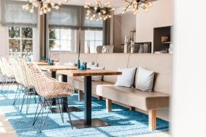 uma sala de jantar com mesas e cadeiras num tapete azul em Hotel Landhaus an de Dün em Sankt Peter-Ording