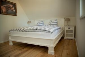 a white bed with blue and white pillows on it at Grüne Hufe in Born