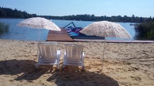two lawn chairs and umbrellas on a beach at Gościniec nad Zalewem Sosina in Jaworzno +56 photos