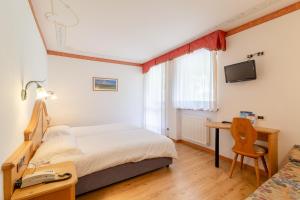 1 dormitorio con 1 cama y escritorio con ordenador en Hotel Garni la Stua, en Selva di Cadore