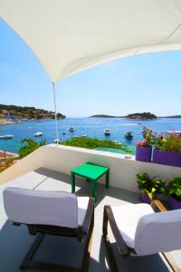 Un balcón con 2 sillas y una mesa verde. en Seafront rooms en Hvar