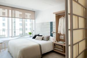 1 dormitorio con cama blanca y ventana grande en Eric Vökel Boutique Apartments - Hamburg Suites en Hamburgo