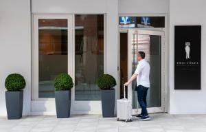 a man standing outside of a building with a suitcase at Eric Vökel Boutique Apartments - Hamburg Suites in Hamburg