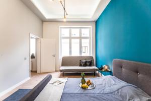 Schlafzimmer mit blauen Wänden, einem Bett und einem Stuhl in der Unterkunft Highrise Oasis Apartment in Budapest