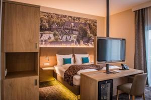 a bedroom with a bed, desk and television at AKZENT Hotel Villa Saxer in Goslar