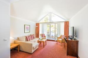 a living room with a couch and a tv at Bel Air Strandhotel Glowe in Glowe