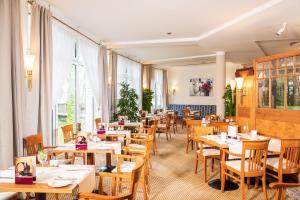 ein Restaurant mit Holztischen, Stühlen und Fenstern in der Unterkunft Bel Air Strandhotel Glowe in Glowe