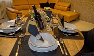 een houten tafel met borden, vorken en glazen erop bij Apartman Nia in Zadar