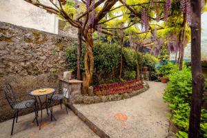 un jardín con mesa, sillas y flores en Il Roseto B&B en Ravello