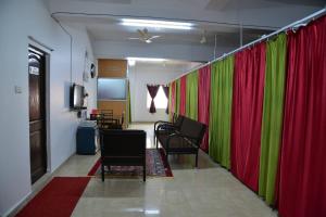 a room with red and green curtains and chairs at Tranquil Hospitality in Bhubaneshwar