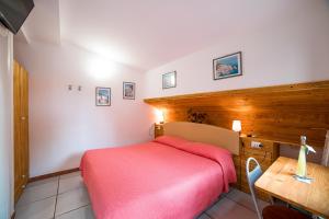 Habitación pequeña con cama roja y escritorio. en Il Roseto B&B en Ravello